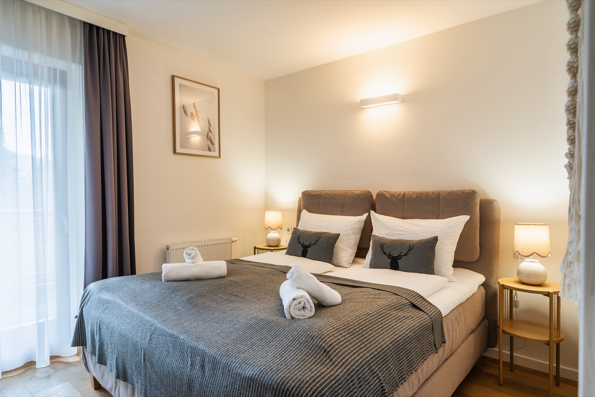 Elegantes Schlafzimmer mit Boxspringbett, gefalteten Handtüchern und Alpenmotiv-Kissen im Alpstay Chalet Bad Kleinkirchheim – Ferienwohnung Fotografie Kärnten
