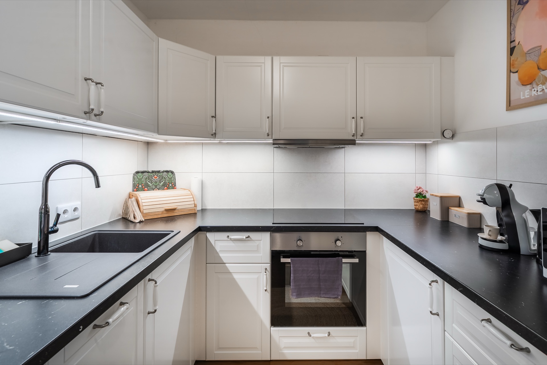 Vollausgestattete weiße Einbauküche mit schwarzer Arbeitsplatte, Backofen, Nespresso-Maschine und Herdplatten im Alpstay Chalet Nr.1 Bad Kleinkirchheim – Küchenfotografie Ferienwohnung Kärnten