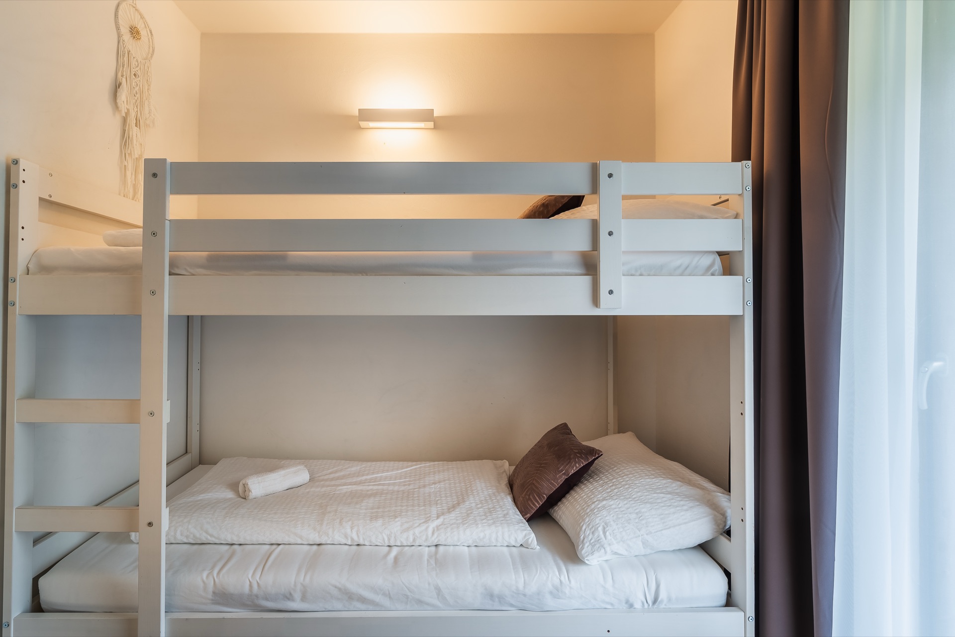 Helles Kinderzimmer mit weißem Etagenbett, großem Fenster und Dreamcatcher im Alpstay Chalet Nr.1 Bad Kleinkirchheim – familienfreundliche Ferienwohnung Fotografie Kärnten